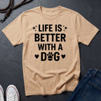 Beige Comfort Colors t-shirt with 'Life is better with a dog' text on a dark surface.