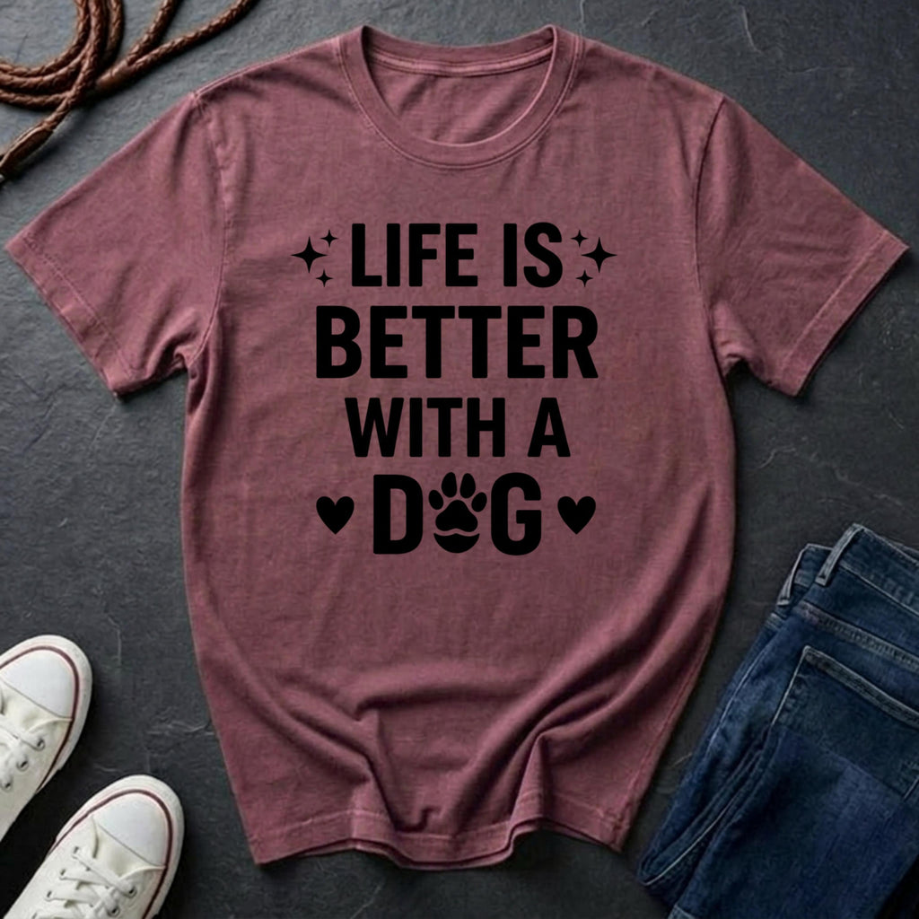 Maroon Comfort Colors t-shirt with 'Life is better with a dog' text on a dark surface with shoes and jeans.