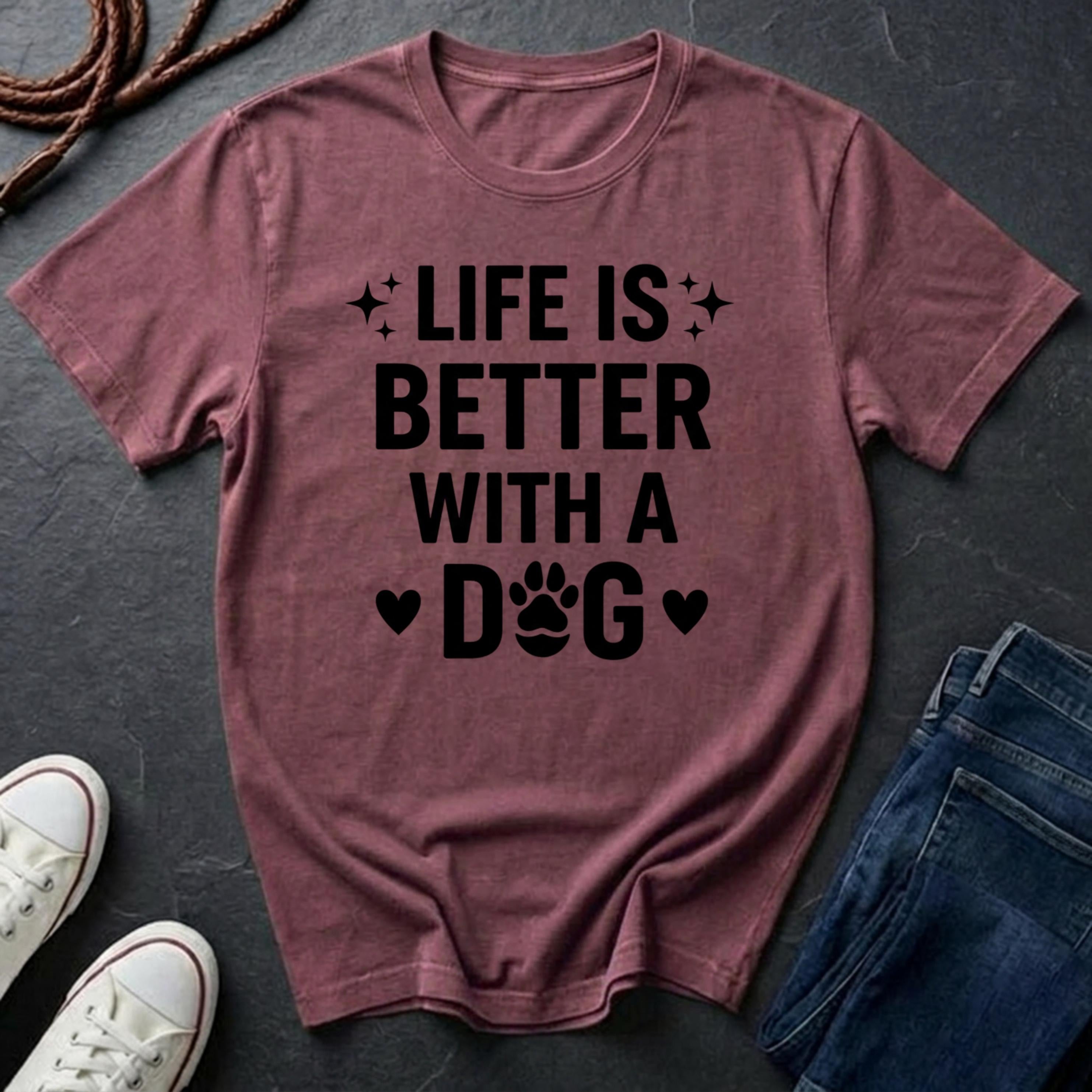 Maroon Comfort Colors t-shirt with 'Life is better with a dog' text on a dark surface with shoes and jeans.