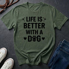 Green Comfort Colors t-shirt with 'Life is better with a dog' text on a dark surface with shoes and jeans.