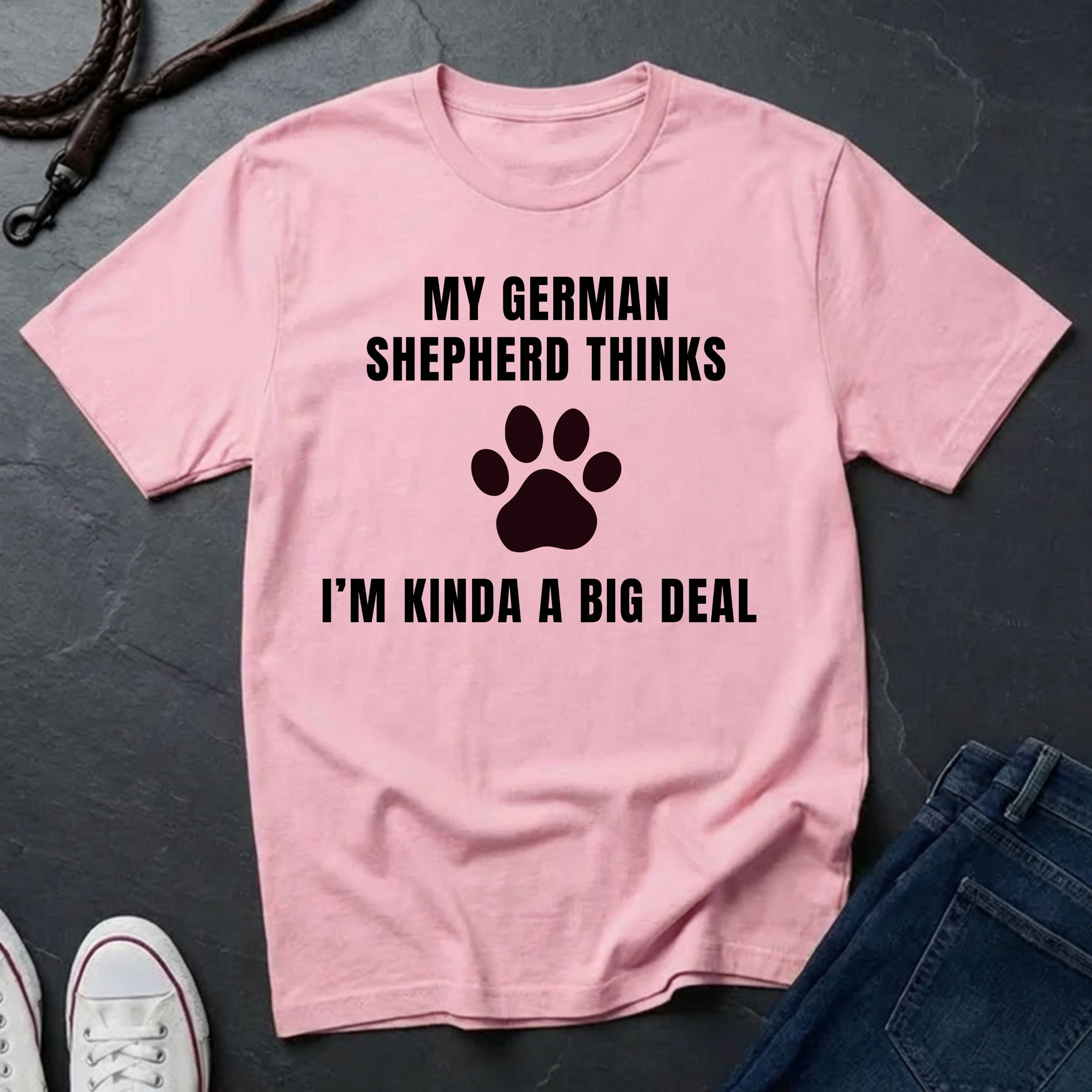 Pink Comfort Colors t-shirt with text and paw print design on a dark surface with jeans and shoes.