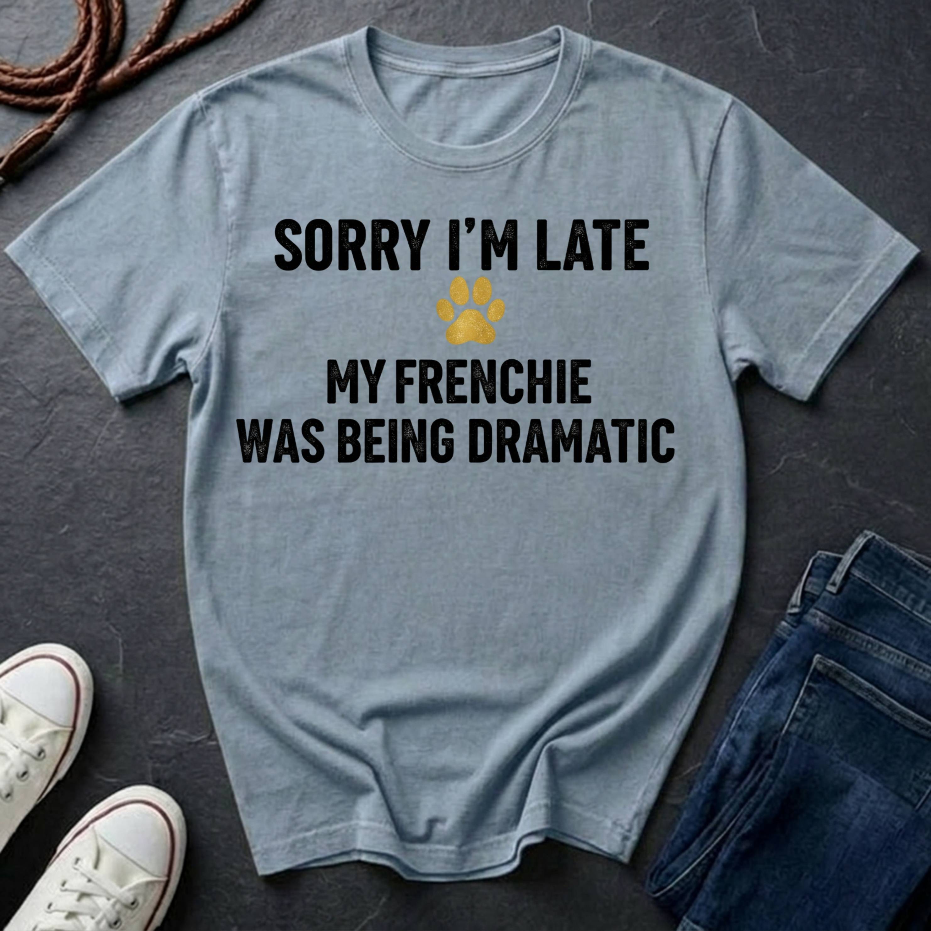 Gray Comfort Colors t-shirt with humorous text design on a dark surface with shoes and jeans.