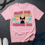 Pink Comfort Colors t-shirt with 'Beach Hair Don't Care Frenchie Mom' design on a dark surface.