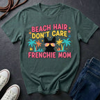 Green Comfort Colors t-shirt with 'Beach Hair Don't Care Frenchie Mom' design on a dark surface with shoes and jeans.