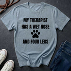 Gray Comfort Colors t-shirt with 'My therapist has a wet nose and four legs' text and paw print on a dark surface.