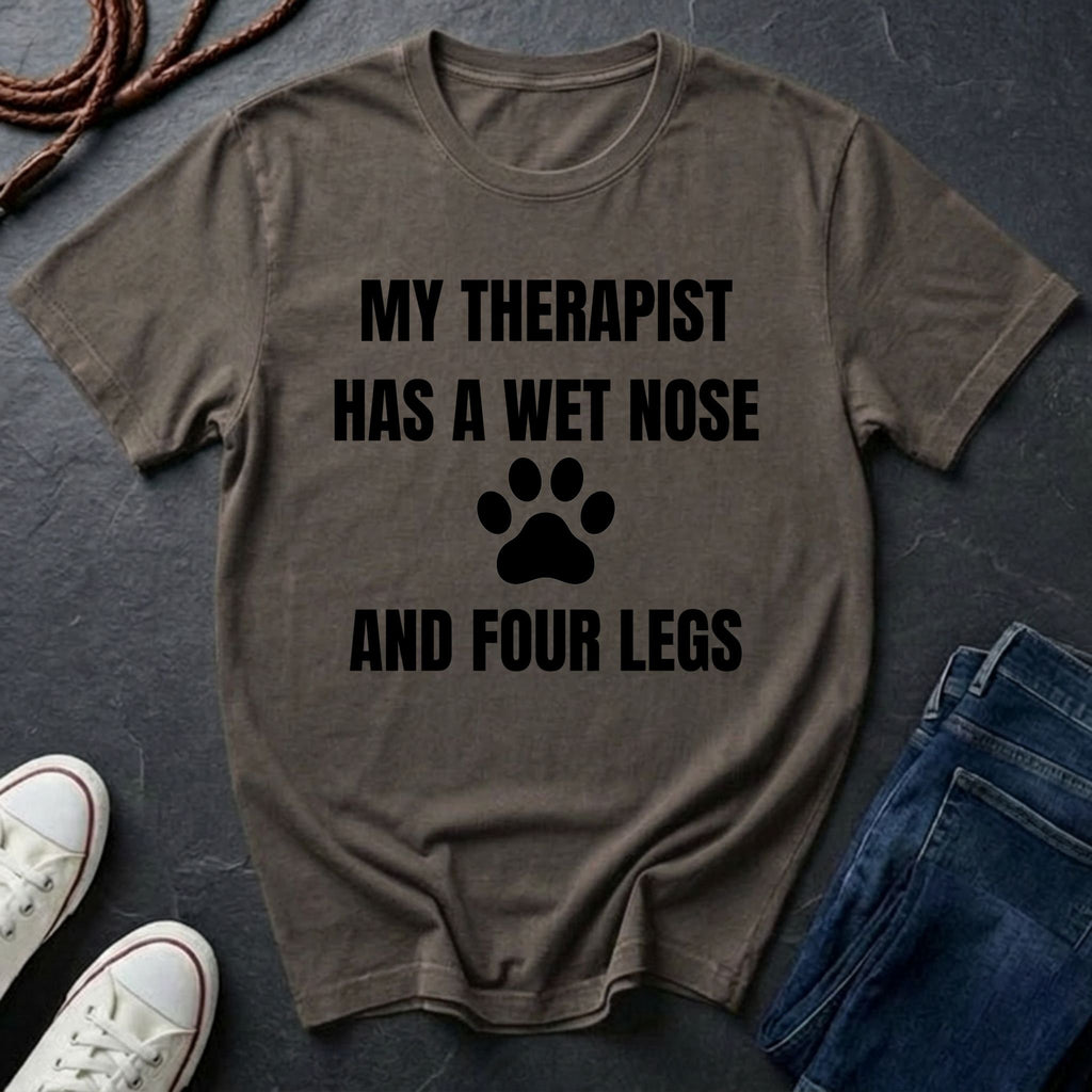 Brown Comfort Colors t-shirt with 'My therapist has a wet nose and four legs' text and paw print on a dark surface.