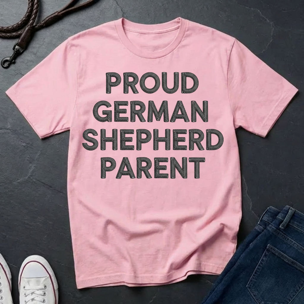 Pink Comfort Colors t-shirt with 'Proud German Shepherd Parent' text on a dark surface with jeans and shoes.