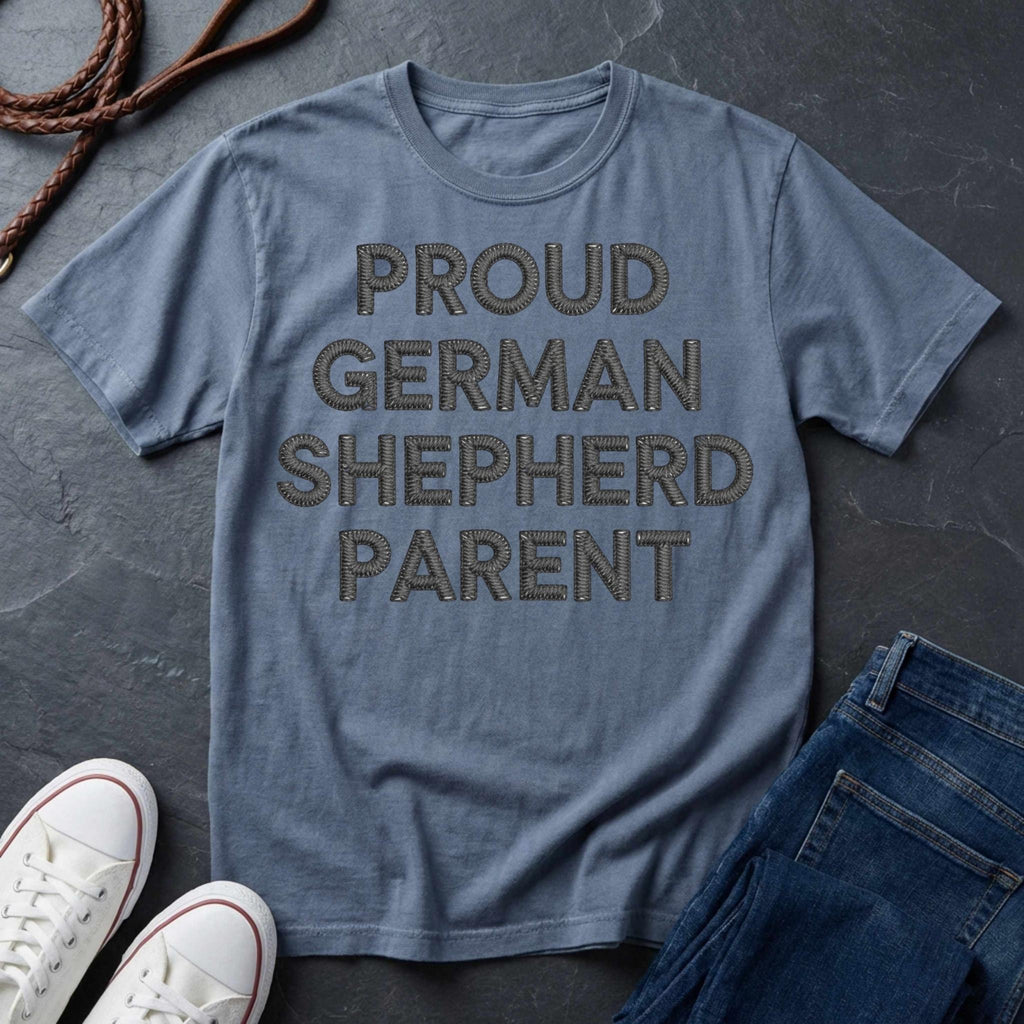 Blue Comfort Colors t-shirt with 'PROUD GERMAN SHEPHERD PARENT' text on a dark surface with shoes and jeans.