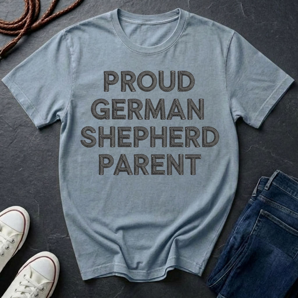 Blue Comfort Colors t-shirt with 'Proud German Shepherd Parent' text on a dark surface with shoes and jeans.