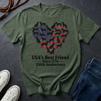 Green Comfort Colors t-shirt with heart-shaped dog design and text on a dark surface with shoes and jeans.