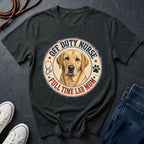 Black Comfort Colors t-shirt with a dog graphic and text on a dark surface with shoes and jeans.