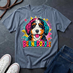 A blue jean short-sleeve comfort colors Tee featuring a colorful pop-art Bernedoodle dog graphic with the word 'BERNEDOODLE' in bright multicolor letters.