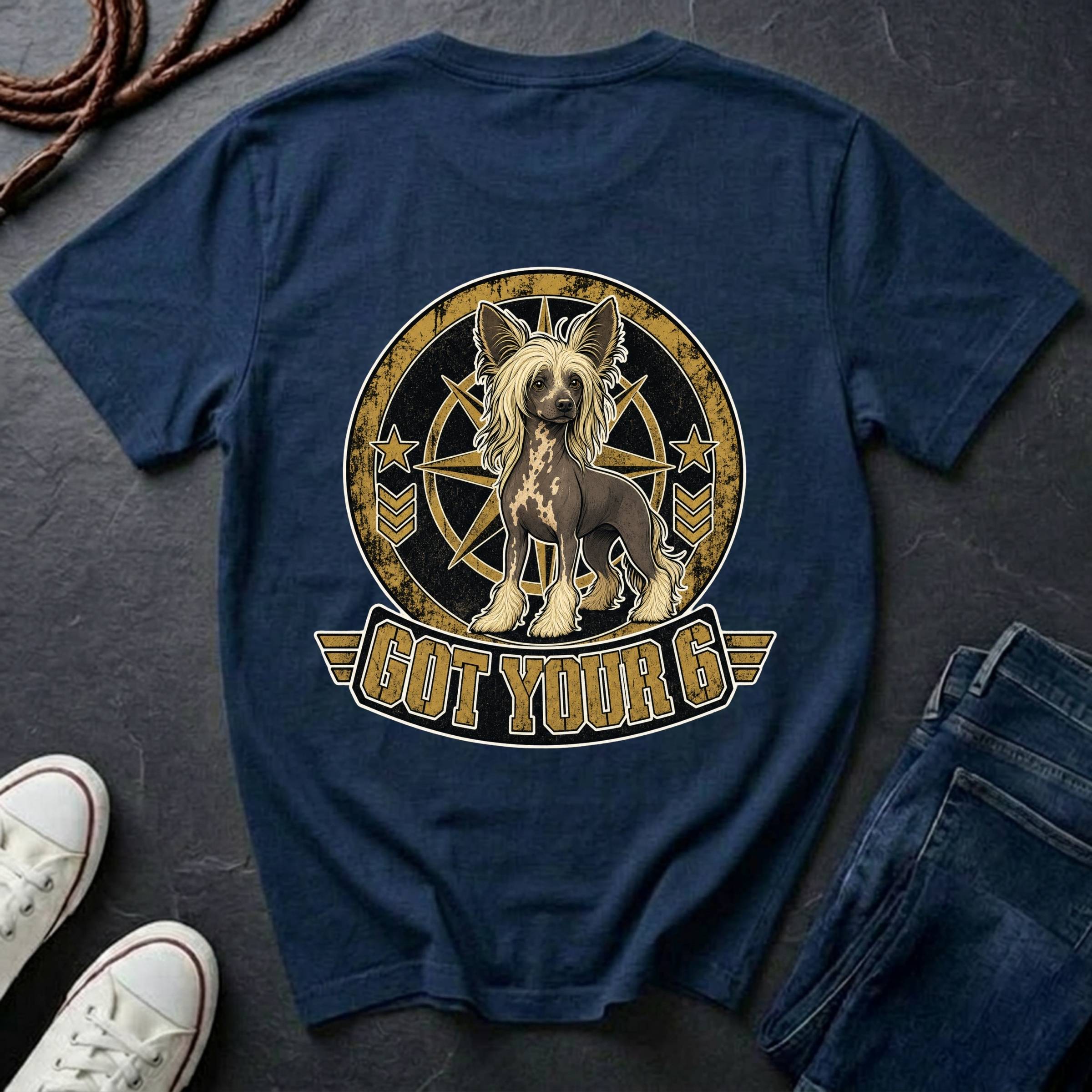 A navy blue graphic t-shirt laid flat on a dark slate background, styled with a pair of blue jeans, white sneakers, and a coiled rope. The back of the shirt features a large circular graphic of a Chinese Crested dog inside a compass design with the text 'GOT YOUR 6' below it.